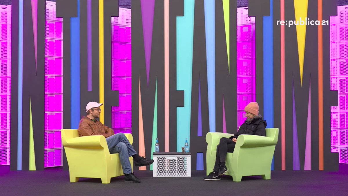 Jean Peters (links) und Carolin Wiedemann (rechts) sitzen sich in großen bunten Sesseln auf der Bühne der rp21 gegenüber.