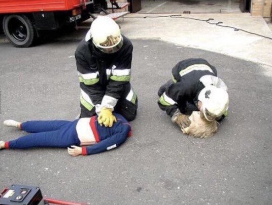 Zwei Feuerwehrleute wiederbeleben eine Puppe Kopf und Toros liegen aber getrennt voneinander.