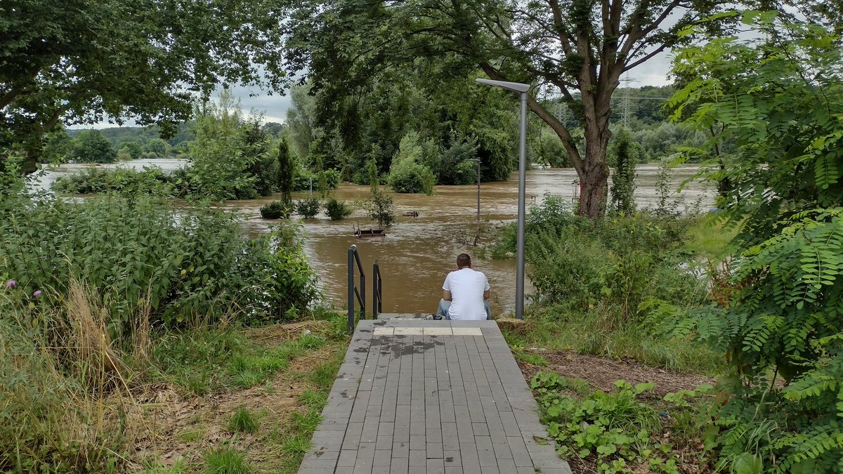 Einsam am überfluteten Ufer sitzender Mann.