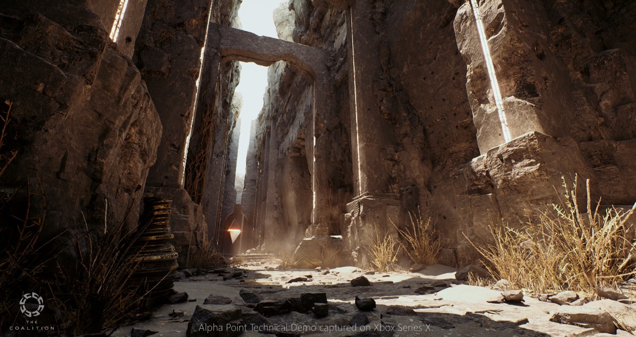 Shot from The Coalition's Alpha Point Technical Demo captured on the Xbox Series X. The scene shows an old tall building ruin made of stone. Brown and grey tones run through the image with light shining down from the sky. 