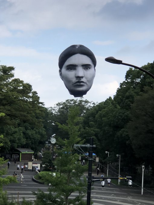 A Giant Head Hot Air Balloon Floats Over A Tokyo Park