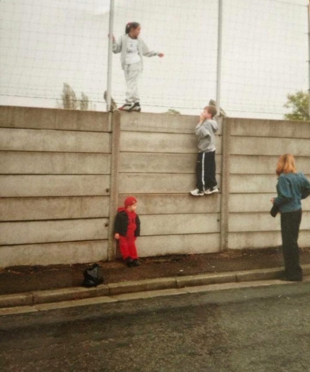 A young Daniel Melia climbing the Melwood walls to get a glimpse of Gérard Houllier's treble winning team in 2001. #LFC #thisismelwood