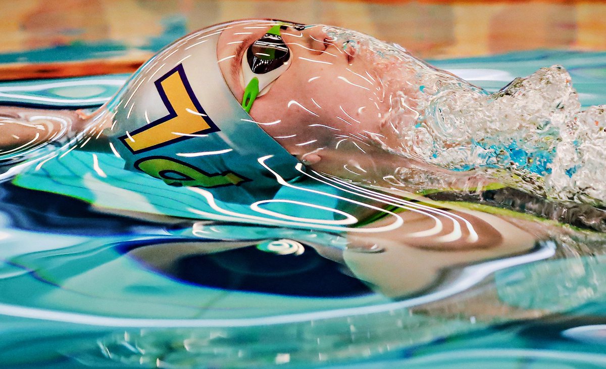 A swimmer at the surface of the water before breaking the surface tension, making it look like they're trapped in plastic