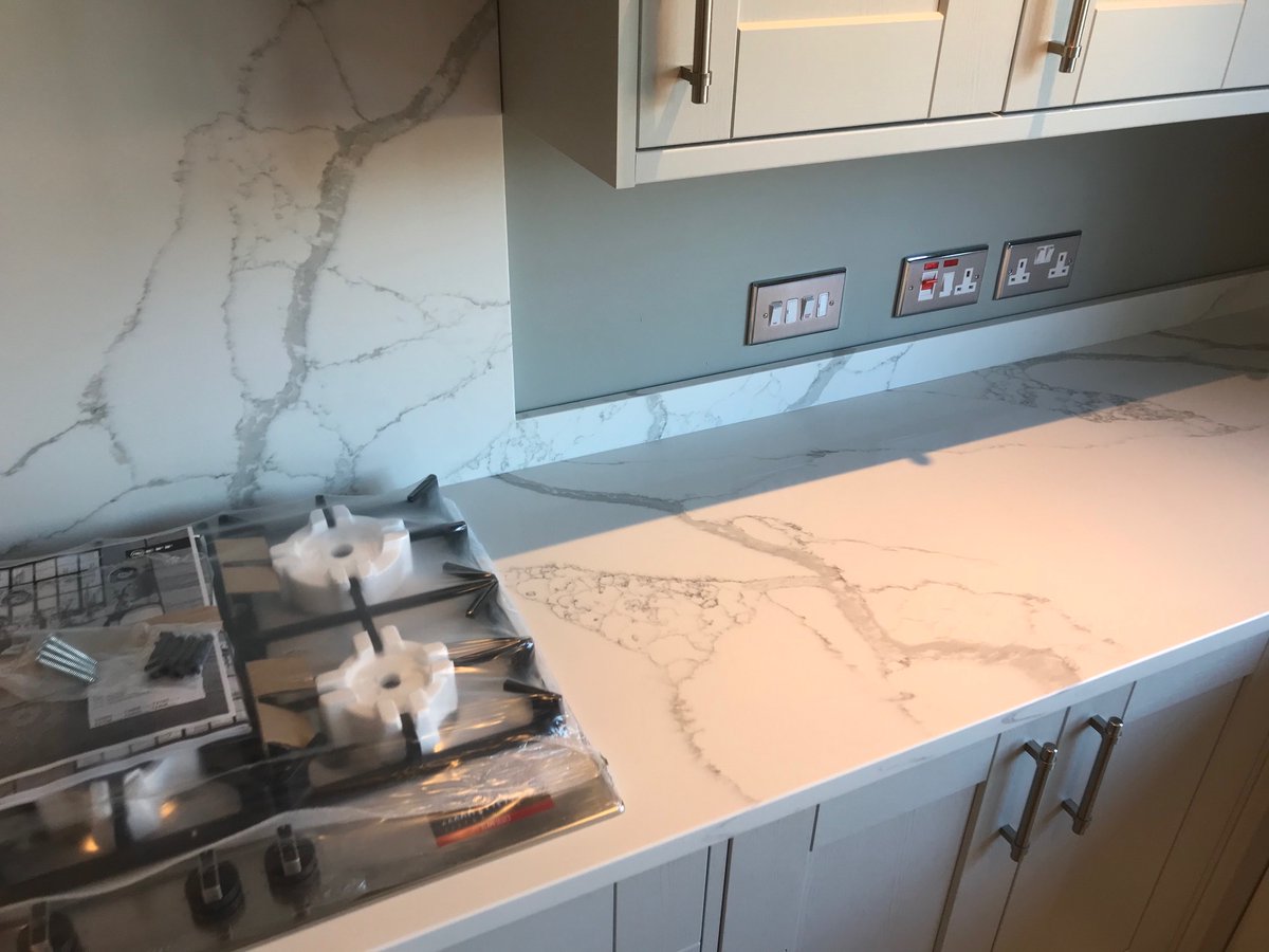 Caldia Quartz by Global gives any kitchen a luxurious feel, with it's genuinely timeless look. this kitchen in particular features upstands connecting to the windowsill and stunning a hob splashback.
