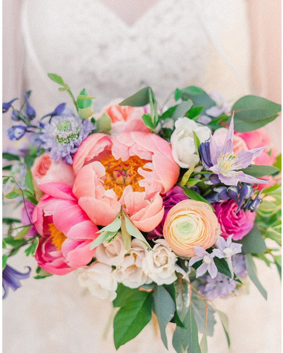 If this isn't #summerweddinggoals we don't know what is. Coral charm peonies, peachy ranunculus, and the most incredible lavender clematis vine are the most swoon-worthy combination for a sweet bride.  #summerwedding #bridalbouquet #bouquetgoals #bridalstyle #weddingtrends #coral