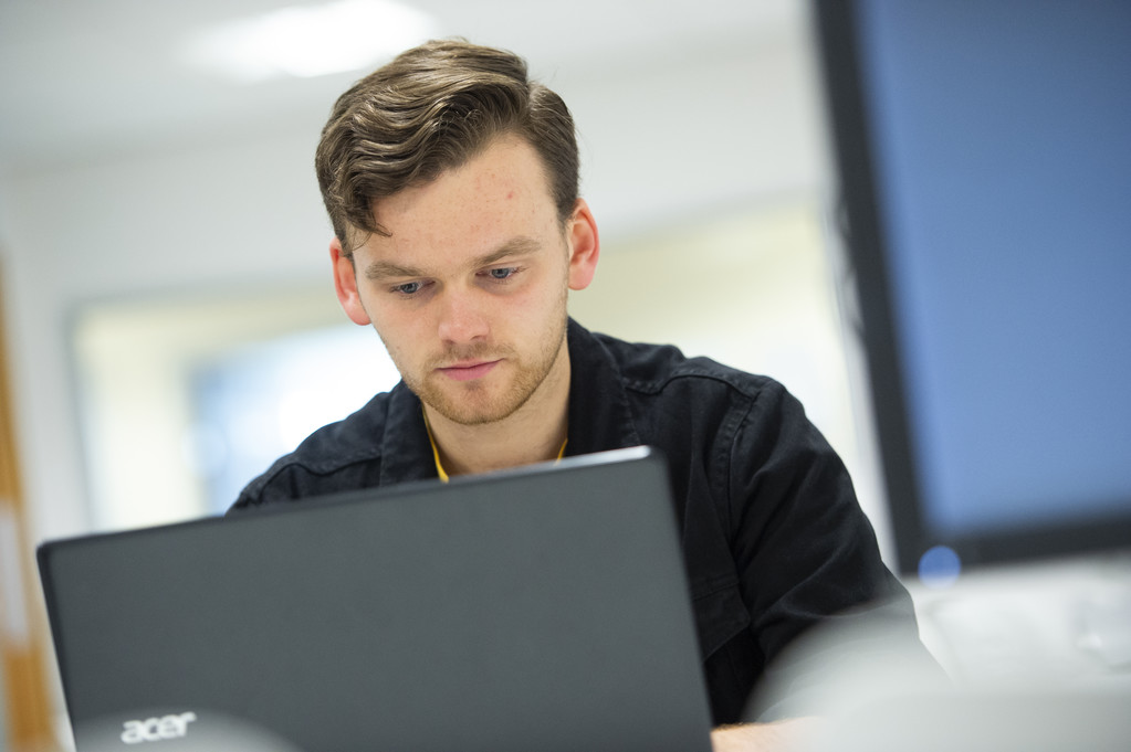A young male student looks at a laptop screen.