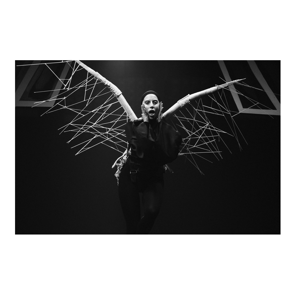 'Applause' M/V look no. 3: next, Gaga wears a black bell-sleeved catsuit from Italian label #MilaSchön F/W13 collection, custom umbrella, bandage &amp; wood wings by <a href="/JunkerDesigns/">JunkerDesigns</a> and her #AzzedineAlaia F/W12 boots.