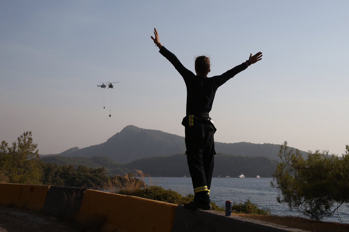 Marmaris Hisarönü’nde helikopterden destek istemeye çalışan bir gönüllü. Bölgede çok sayıda gönüllü, yangın söndürme çalışmalarına katılıyor.