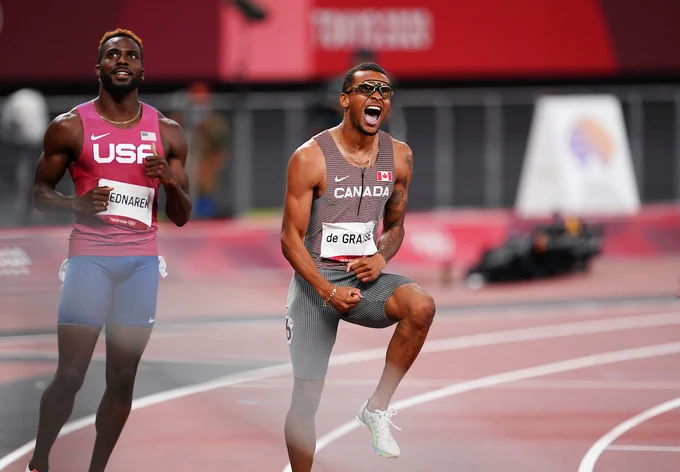 Andre De Grasse celebrates after winning Olympic gold. Standing and yelling.