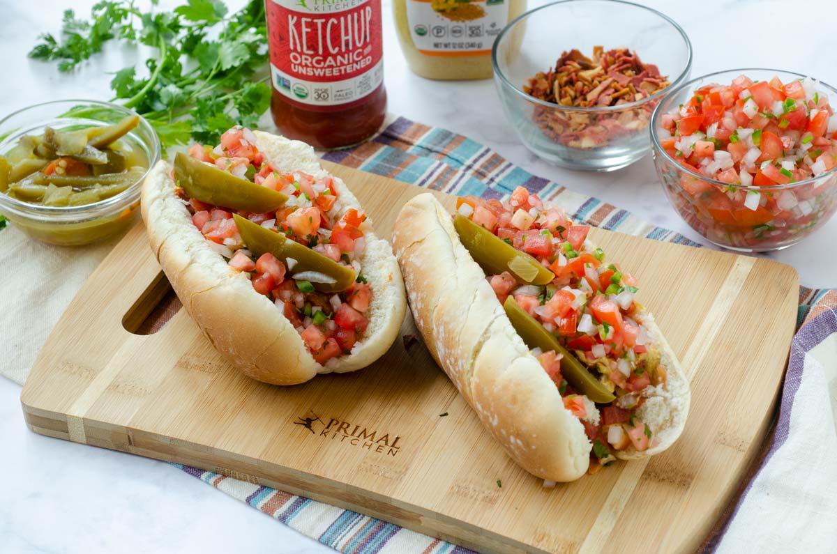 Ridiculously Good Mexican Hot Dogs. Vegan sausage topped with pico de gallo, mustard, ketchup, mayonnaise, pickled jalapeño peppers, and vegan bacon. Served on a warm toasted bun. Made with <a href="/PrimalKitchenCo/">Primal Kitchen</a> Unsweetened Ketchup #ad #vegan #veganmexican     t.ly/WQTC