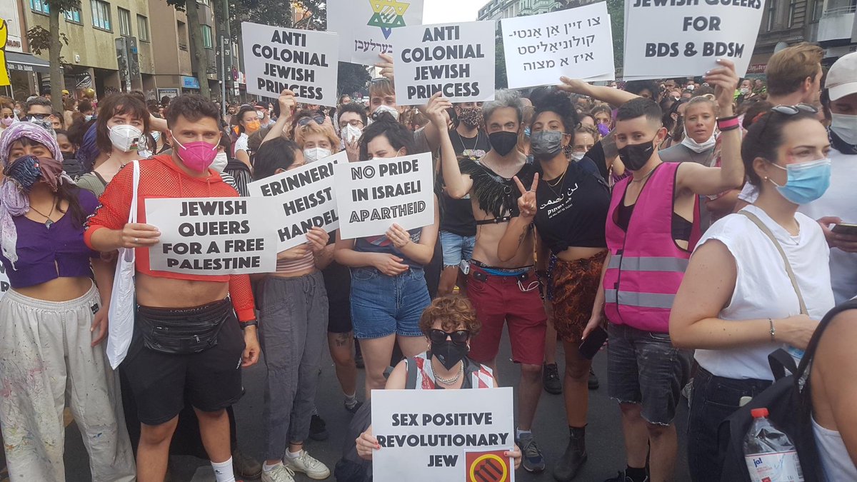 Group photo of a dozen Jewish Bund members holding various signs in English, Hebrew and Yiddish "Anti colonial jewish princess", "Jewish Queers for BDS and BDSM", "No pride in Israeli Apartheid"