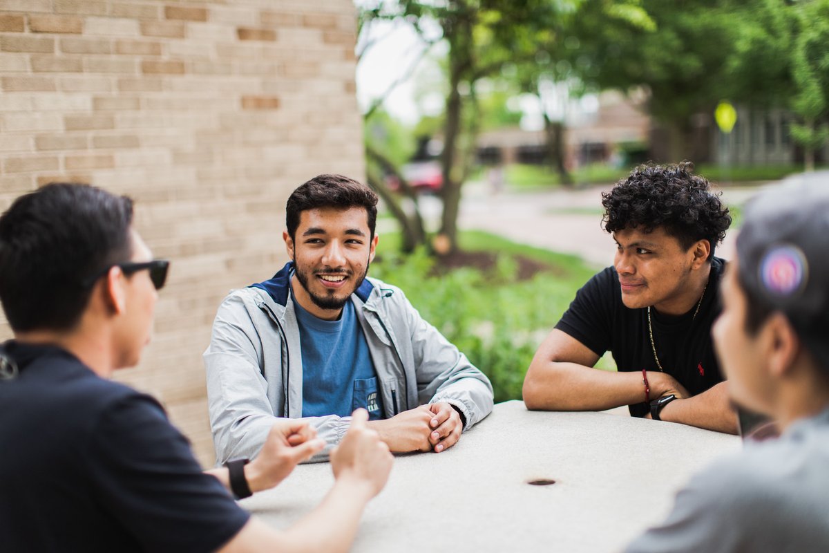 A photo of North Central College student sitting at a table and talking to one another.
