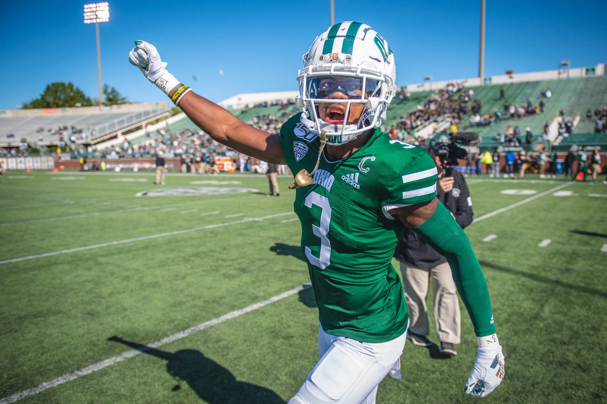 Ohio football player runs with his hand in the air.