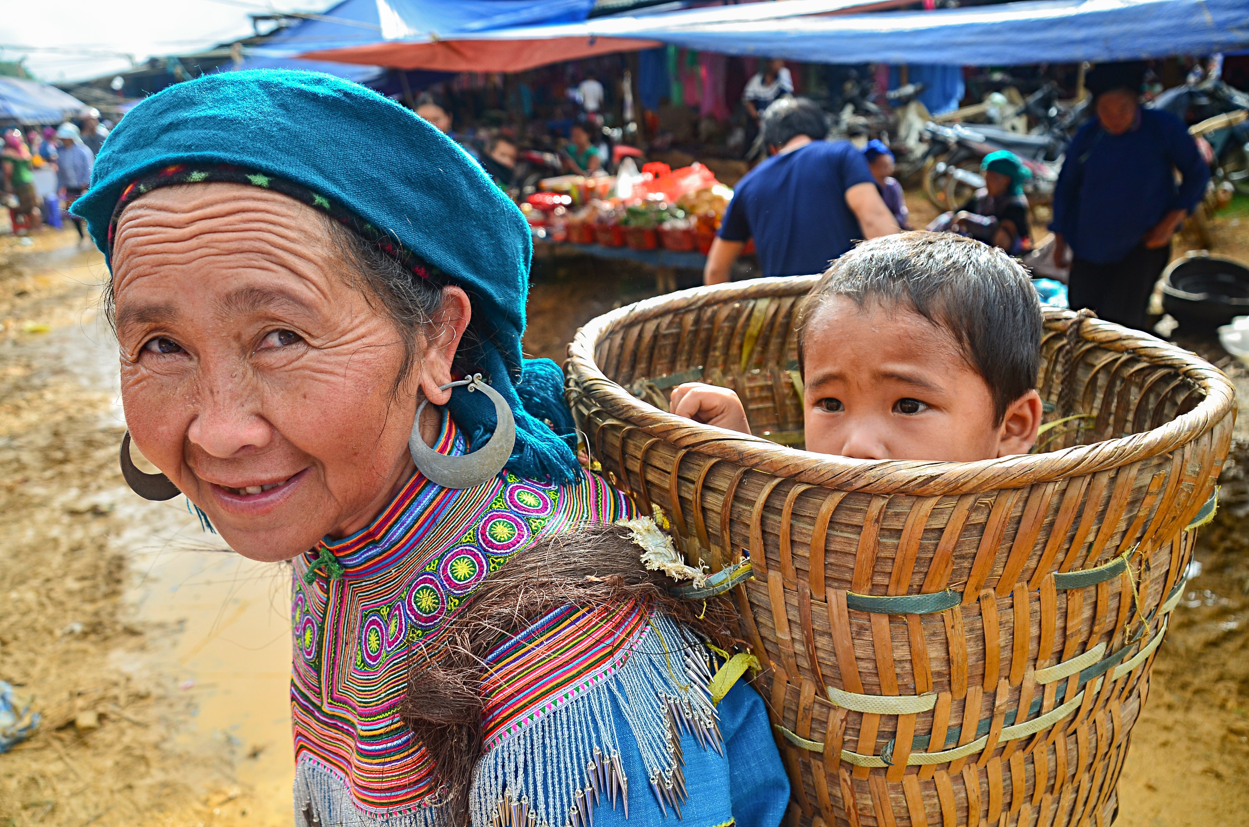 武藤弘司 アジアの家族 おんぶシリーズ ベトナムの市場 花モン族の女性が 竹籠に男の子を入れていた 祖母と孫だろう 優しそうな おばあさんだった ２０１５年 ベトナム アジア ベトナム おんぶ アジアのおんぶ ベトナムのおんぶ 花