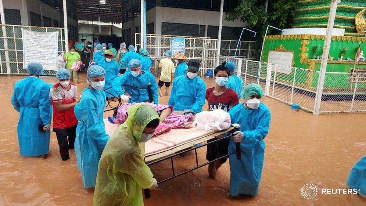 Volunteers in protective suits carry a COVID-19 patient as they try to relocate due to the flood in Myawaddy, Karen state, Myanmar, July 26, 2021, in this handout imaged obtained by Reuters on July 27, 2021.  Karen Information Center/Handout via REUTERS