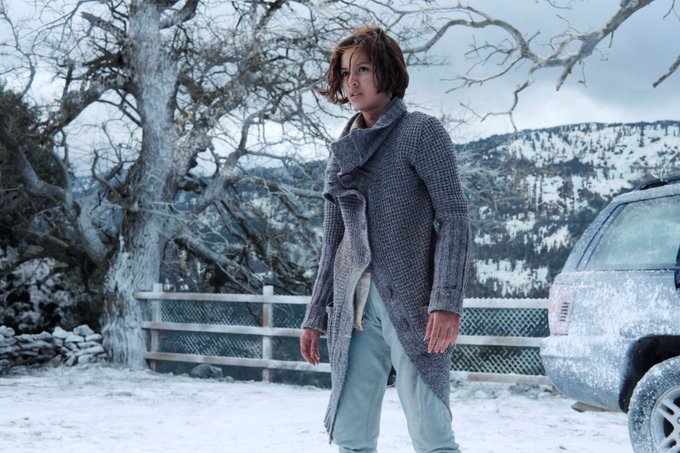 Irene Virgüez stands alone in a winter countryside with a truck and a mountain behind her, looking warily out of frame.