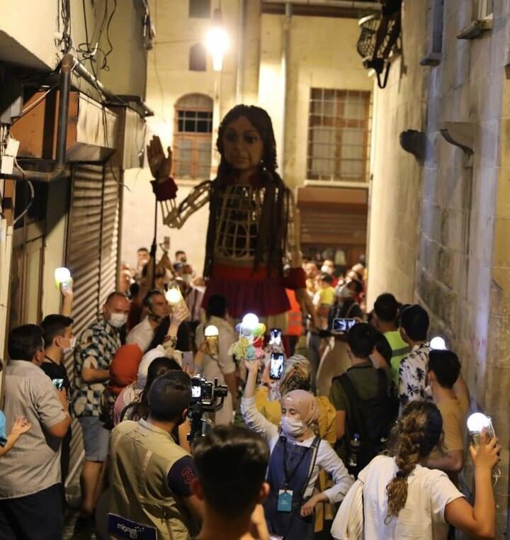 مواطنون أتراك مع دمية عملاقة في مدينة غازي عنتاب ، الدمية تجسد قصة طفلة سورية تسمى أمل. 
الدمية يبلغ طولها 3.5 متر وستنطلق رحلتها من غازي عنتاب إلى إنكلترا لتسليط الضوء على معاناة اللاجئين ومنهم الأطفال