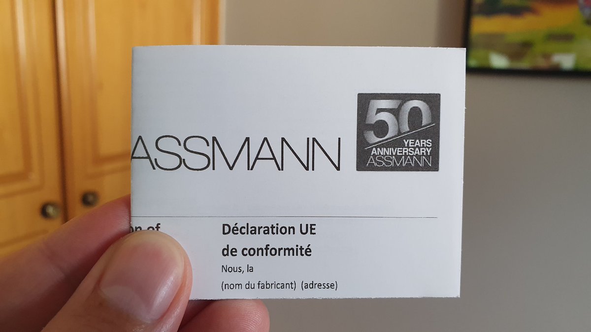 A folded piece of paper with the title "ASSMANN", with a "50 years anniversary Assman" seal.