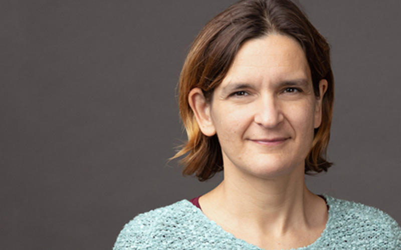 ight head and shoulders picture of Esther Duflo. She is wearing a light blue sweater and she is smiling.