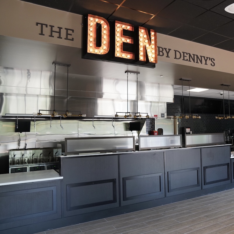 An illuminated sign reading The DEN by Denny's - a new eatery inside Perkins Student Center open this fall.