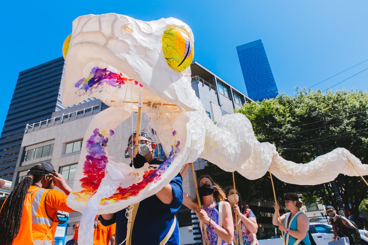 A paper mache snake mascot being help up by five individuals.