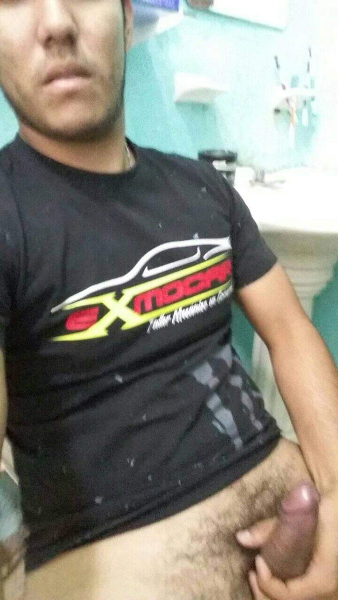 A man in a black undershirt looking seductively over his shoulder his eyes full of playful temptation