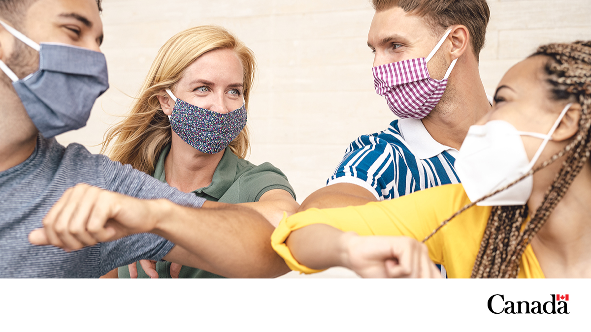 Four friends wearing masks touching elbows. 