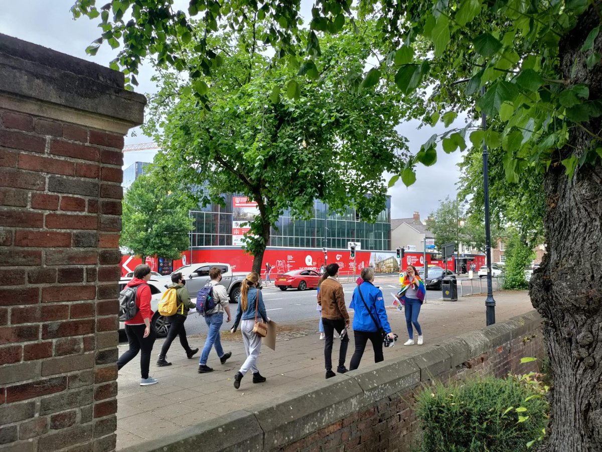 Image shows students and staff walking with Pride flags in front of Queen's University Belfast.