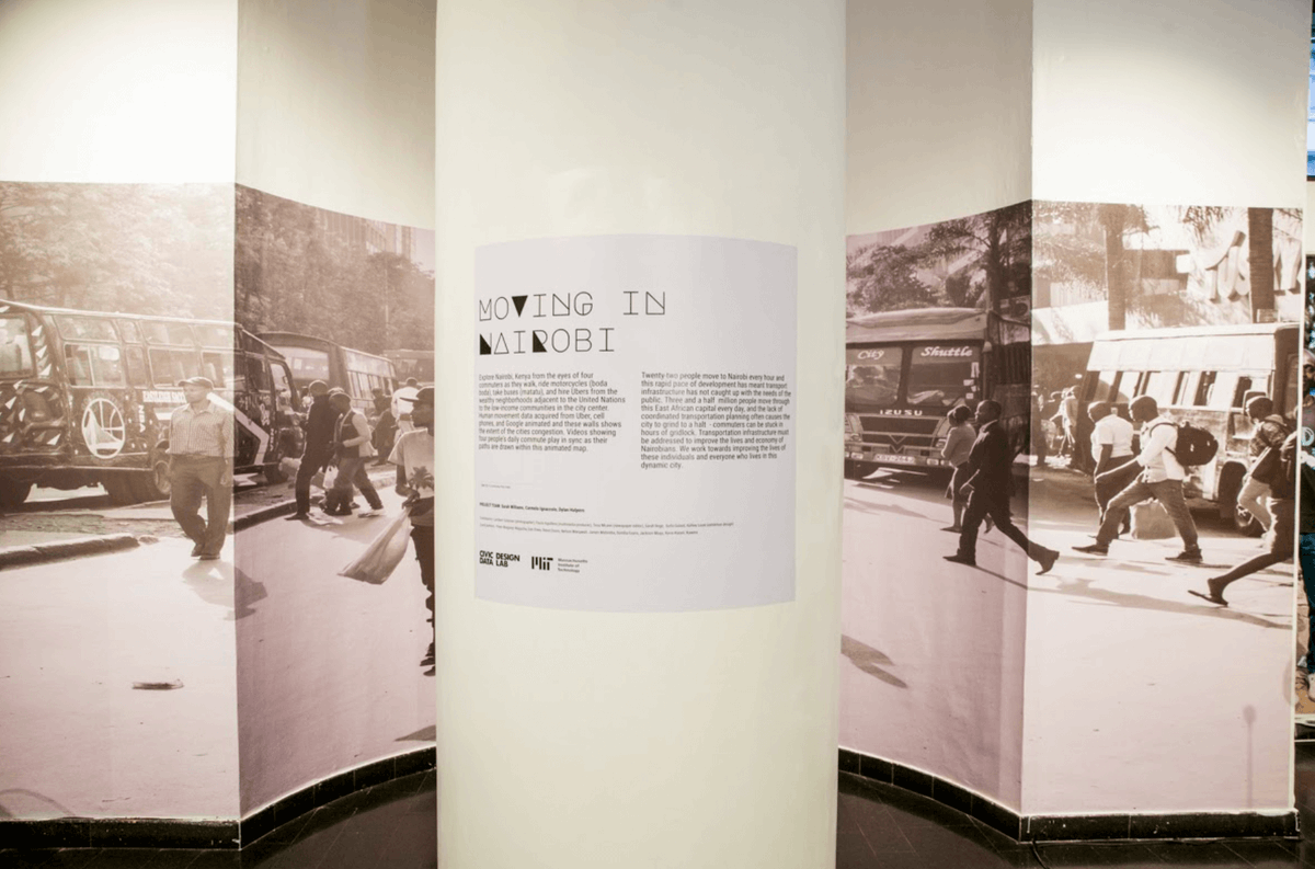 Moving in Nairobi exhibition, a placard that describes the exhibition can been seen in the foreground with images of various types of mobility in the background.