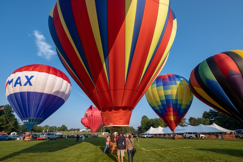 Balloonists and spectators gather around five colorful hot-air balloons during the annual Pro Football Hall of Fame Enshrinement Festival Balloon Classic at Kent State University at Stark. 