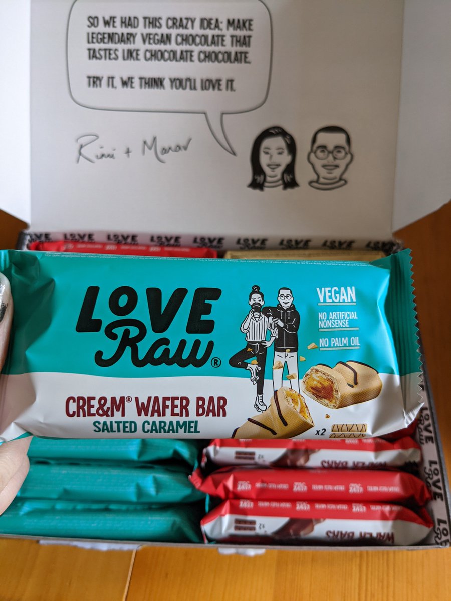 A love raw salted caramel cream wafer bar being held above a box containing other love raw bars