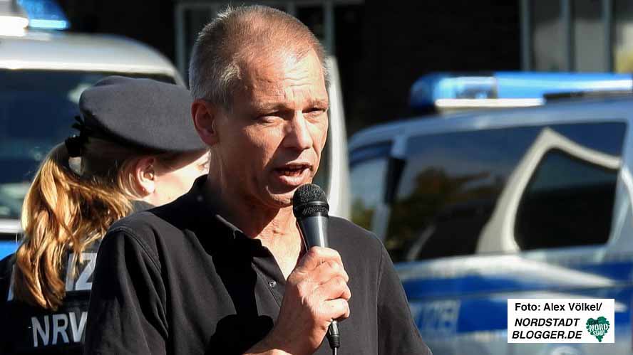 Christian Worch mit einem Mikro in der Hand. Im Hintergrund Polizei.
Foto von Alex VölkelNordstadtblogger.de