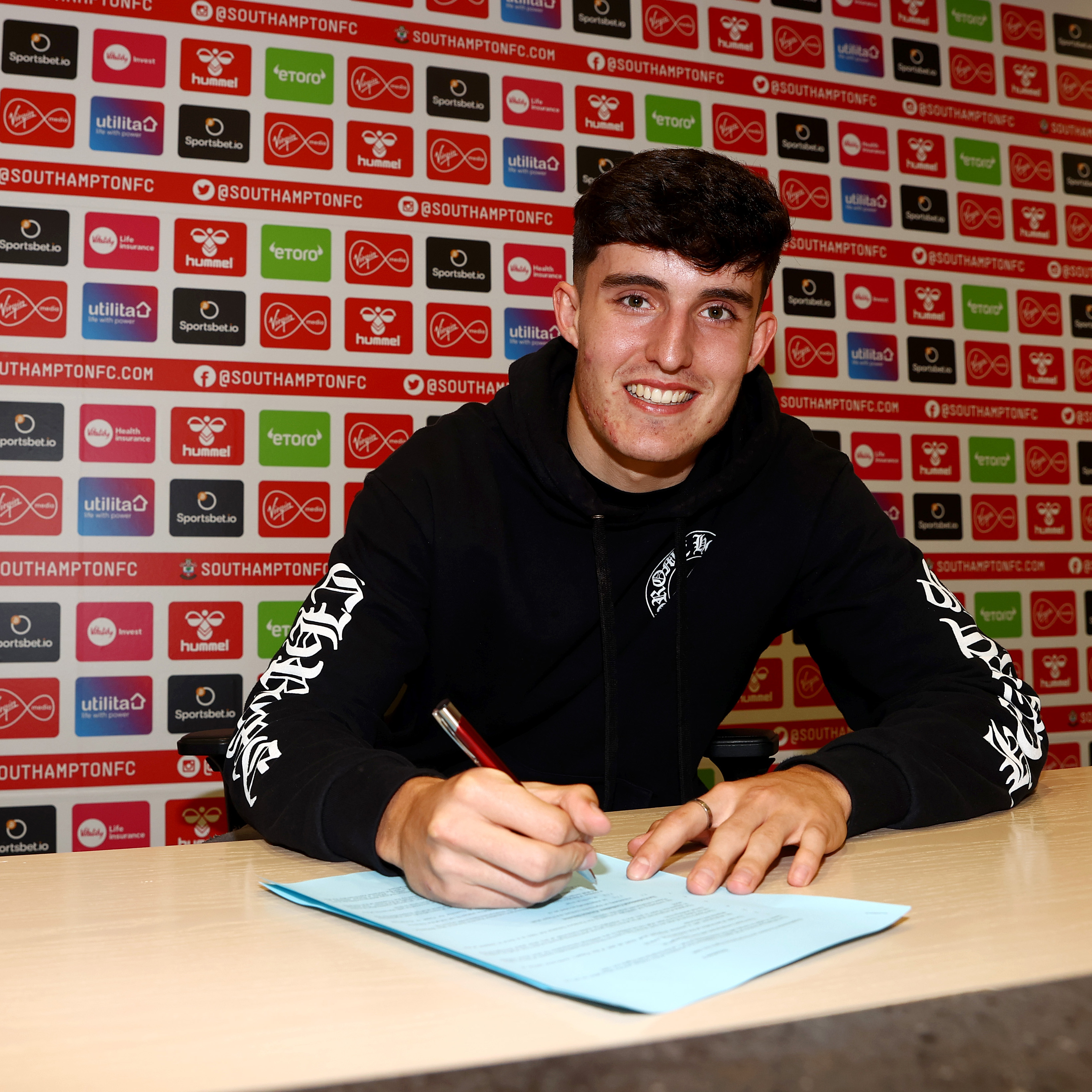 New recruit Tino Livramento signs his paperwork after choosing to make a permanent switch from Chelsea.
