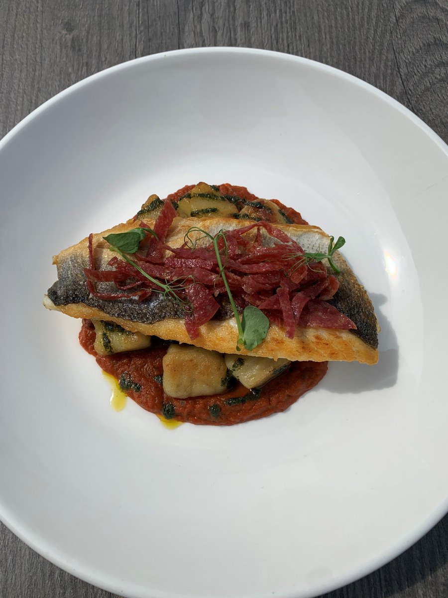 Pan roasted seabass, crispy salami, sauteed potato gnocchi and spinach with a Pomodoro sauce and basil oil