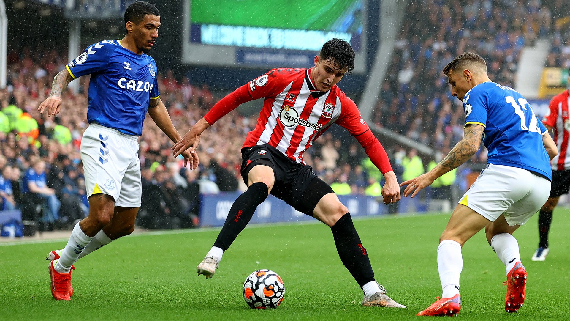 Tino Livramento controls the ball, with two Everton players close by.