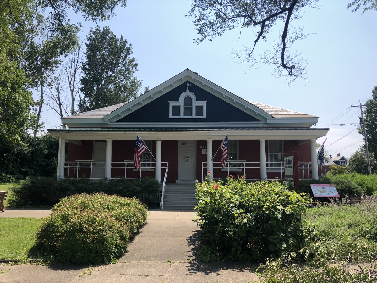 The exterior of the Safe Haven Holocaust Refugee Shelter Museum on a sunny day with two American flags on the porch and shrubs in the foreground