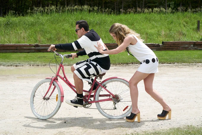 A series of three photos from the episode of Schitt's Creek where Mutt gifted Alexis a bright pink bike. In the first, Alexis (Annie Murphy) struggles to ride the bike as a new learner. In the second, David (Dan Levy) is also struggling with the bike. In the third, David is still on the bike and Alexis is trying to push him from behind. 