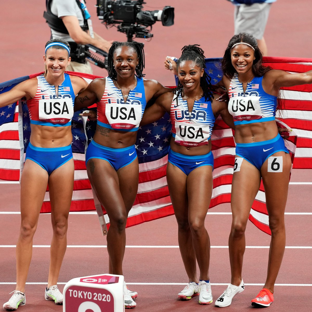 United States 4 by 100 meter relay team draped in four American flags