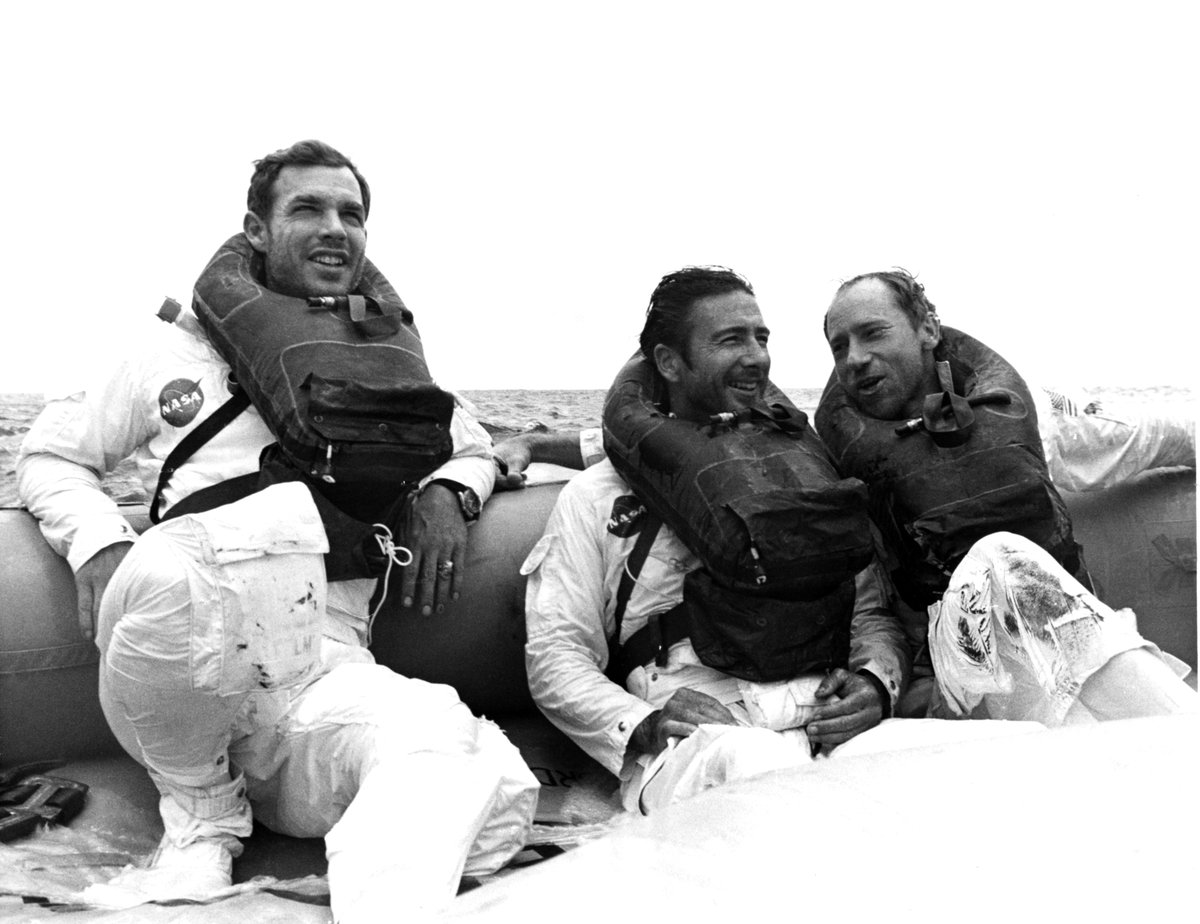 Three astronauts sit in a raft