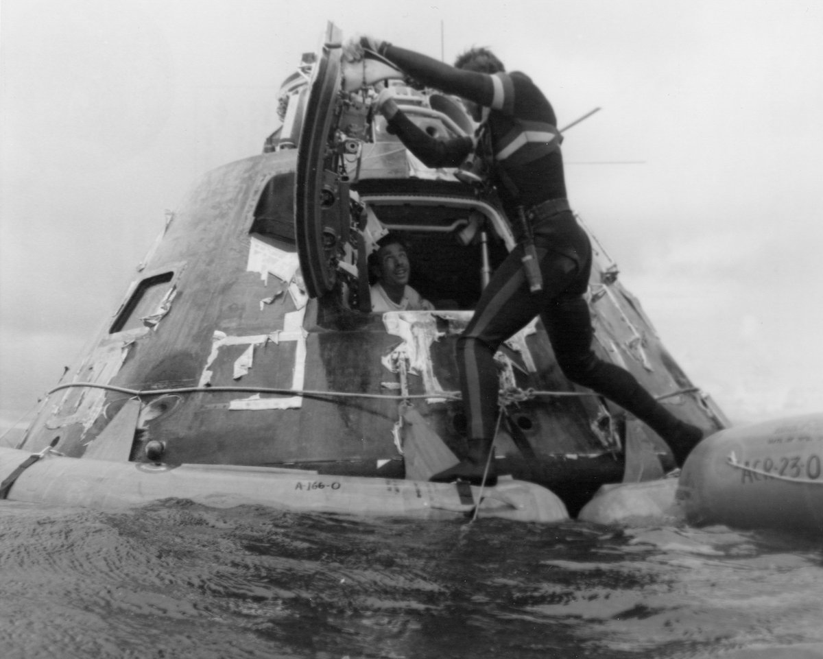 Diver looks into the command module, with an astronaut peeking out