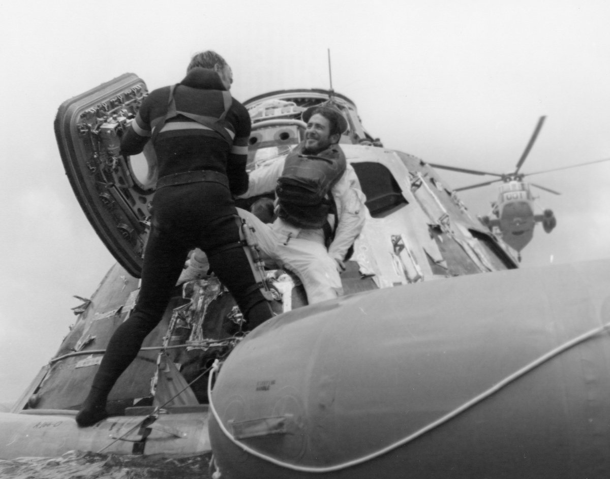 Divers help an astronaut out of the command module