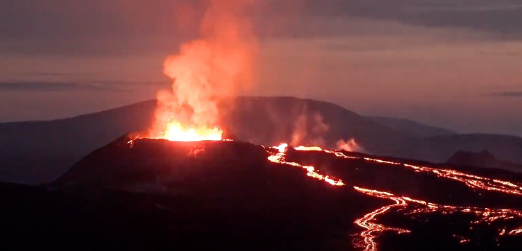 soft pink and blue sky in the background. lava flowing down the volcano