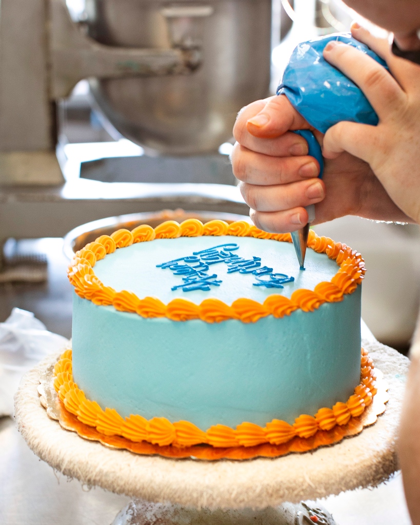 Putting the finishing touch on a brightly-colored cake. 🎂