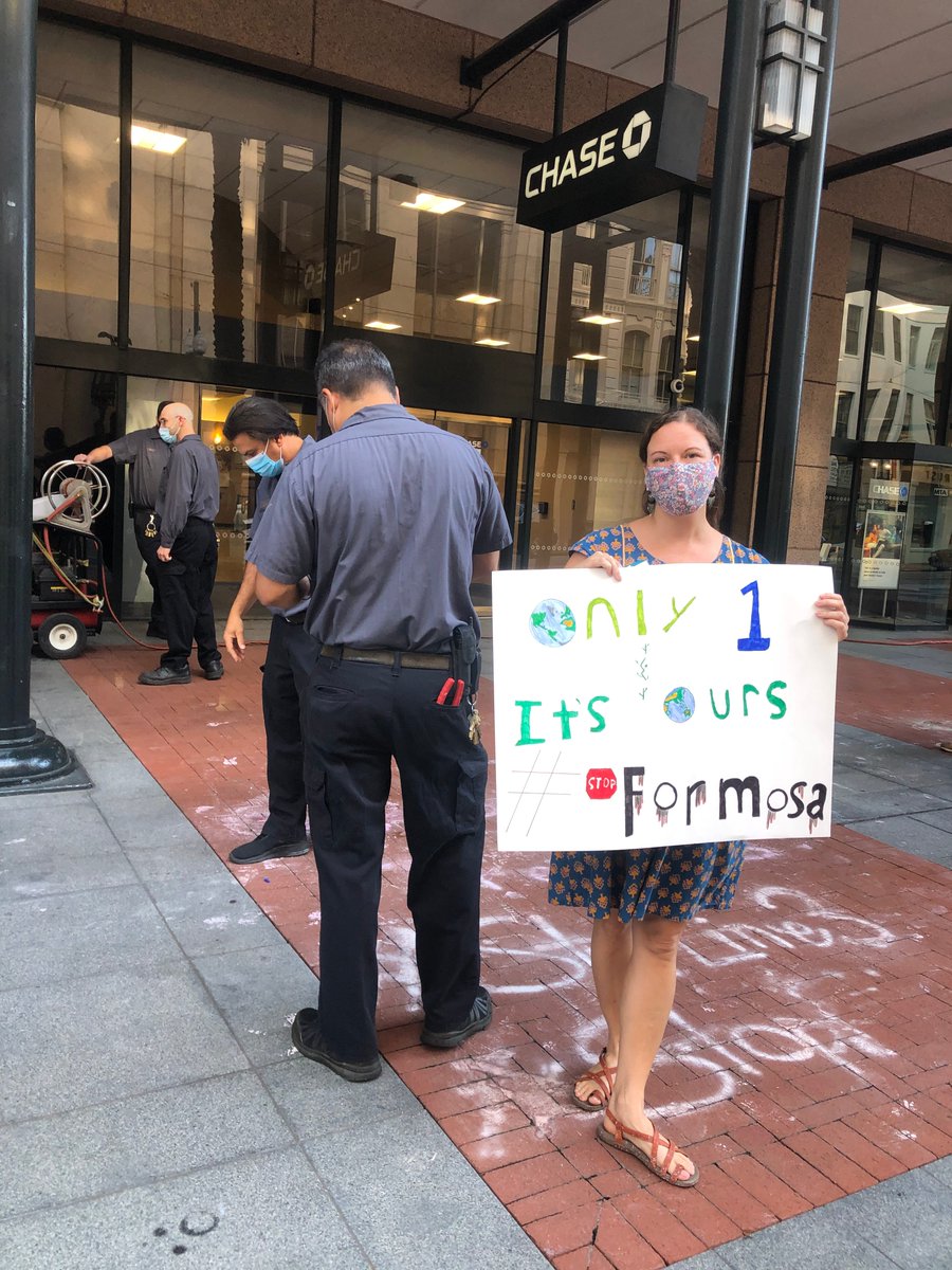 Alison McCrary, Ani-Yun-Wiya Cherokee Nation member, with sign:"Only 1 earth. It's Ours. Stop #Formosa" <a href="/Chase/">Chase</a> bank in New Orleans. Workers remove chalk writing, "Stop #Line3. Respect Treaties. Close Your Account!" on sidewalk. Part of a national day of protest targetting banks.