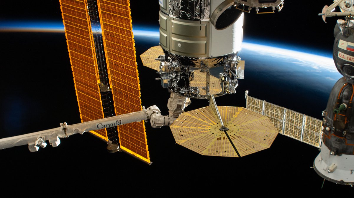 iss065e238807 (Aug. 12, 2021) --- The Northrop Grumman Cygnus space freighter is in the grips of the Canadarm2 robotic arm as it is installed on the International Space Station's Unity module. At left is a portion of one of the orbiting lab's main solar arrays. At right is the Soyuz MS-18 crew ship docked to the Rassvet module. The space station was orbiting into a sunset above far eastern Indonesia at the time of this photograph.