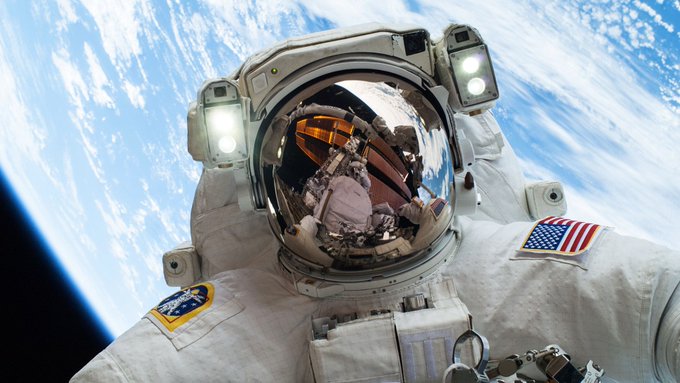 Close up photograph of an astronaut in space with Earth below serving as the backdrop.