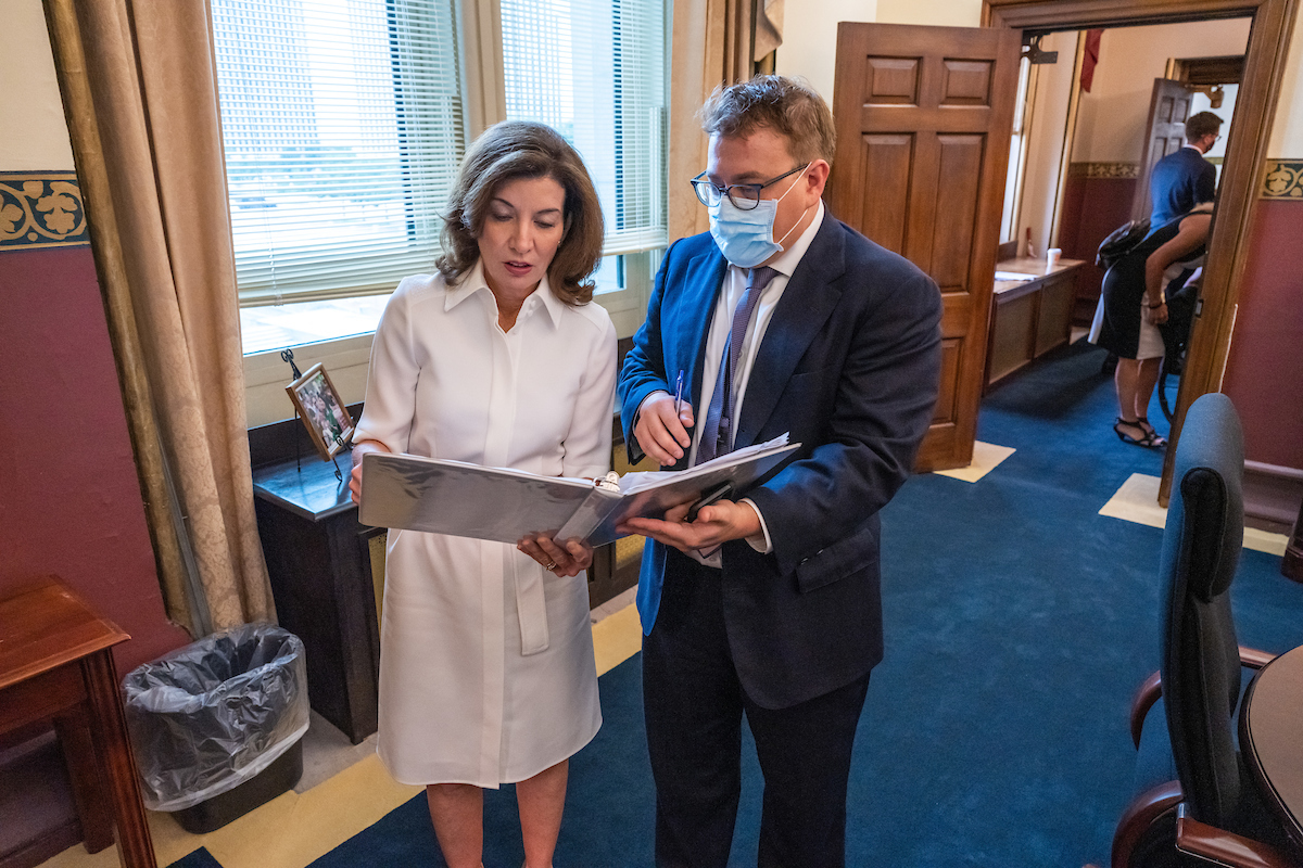 Governor Hochul (left) holds binder with staffer (right)