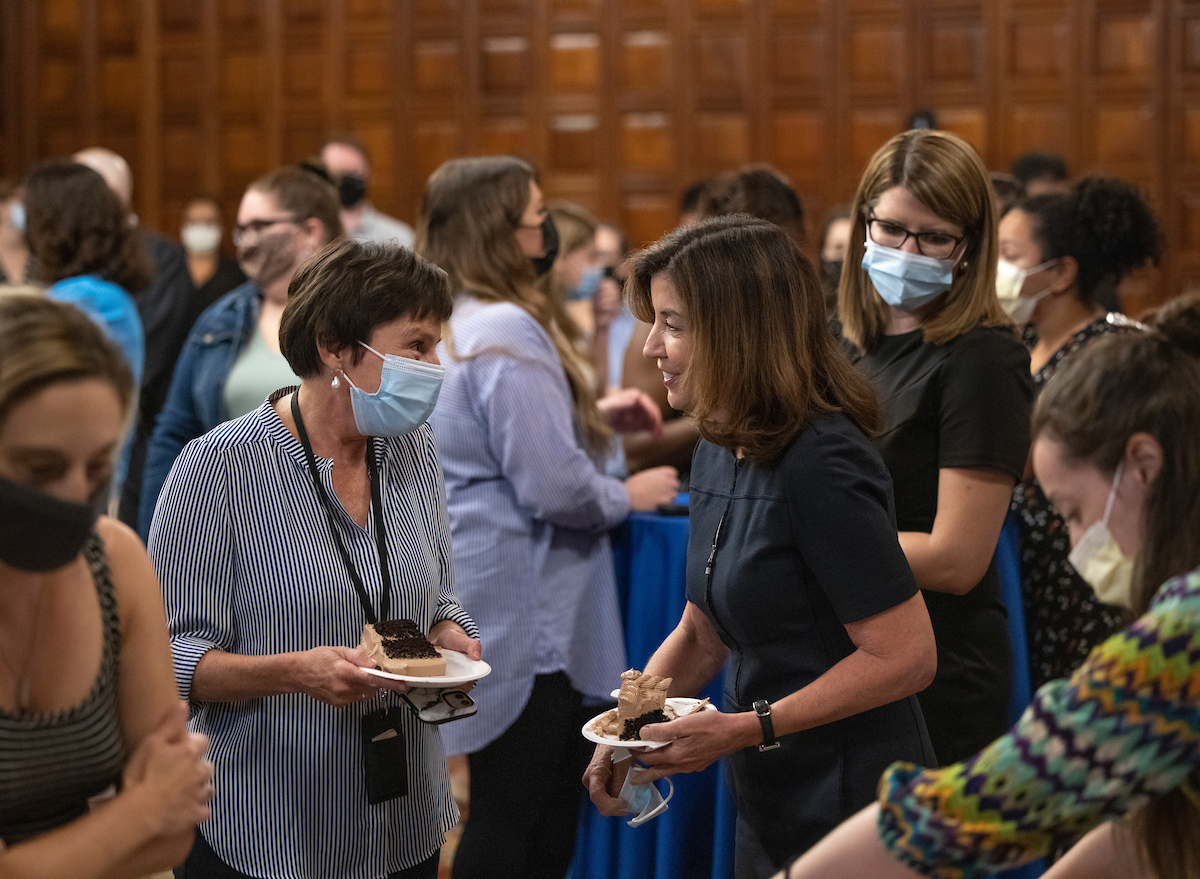 Governor Hochul (right) chats with New York State employee (left) while holding slices of birthday cake