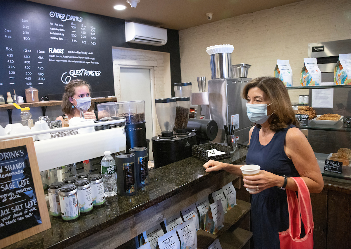 Governor Cuomo wears a mask holding coffee at Stacks Espresso Bar in Albany with masked employee behind the counter. 