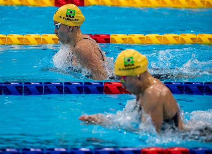 Foto das irmãs Beatriz e Debora nadando a prova de 100m peito. Elas estão bem próximas, mas Beatriz segue um pouco na frente.